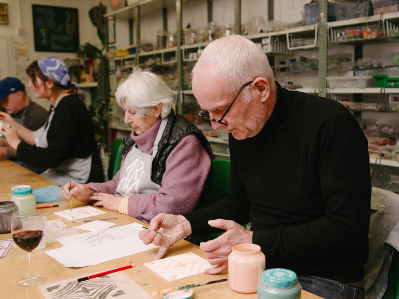 Old couple painting ceramic tiles in a workshop